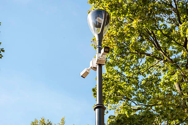 istock Surveillance Cameras on Streetlight Among Trees 2219415654