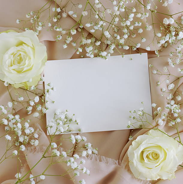 istock Greetings card blank mockup and white flowers frame on beige silk texture background with copy space.T 2219417114