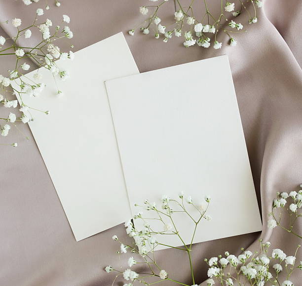 istock Greetings cards blank mockup and white flowers frame on grey silk texture background with copy space 2219417179