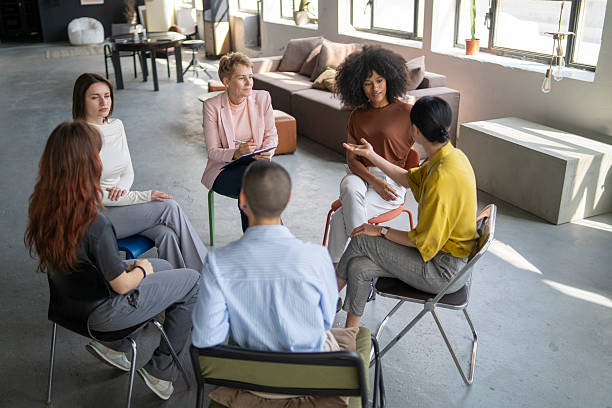 istock Diverse group of people sitting in circle, sharing and discussing in support group meeting 2219417463