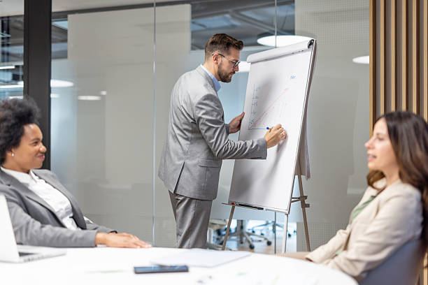 istock Businessman drawing growth chart on flip chart during presentation in office 2219420769