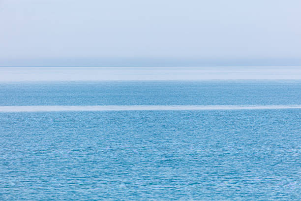 The image is of a calm, clear blue ocean with no visible waves. The water appears to be still and peaceful, creating a serene and tranquil atmosphere