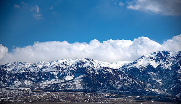 istock The image shows a majestic mountain range covered in snow under a dramatic sky filled with large, fluffy clouds. 2219427577