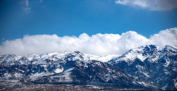 istock The image shows a majestic mountain range covered in snow under a dramatic sky filled with large, fluffy clouds. 2219427594