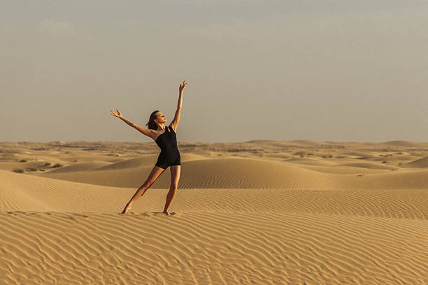 istock Woman practicing dance in desert dunes with serene golden sunset scenery 2219428863