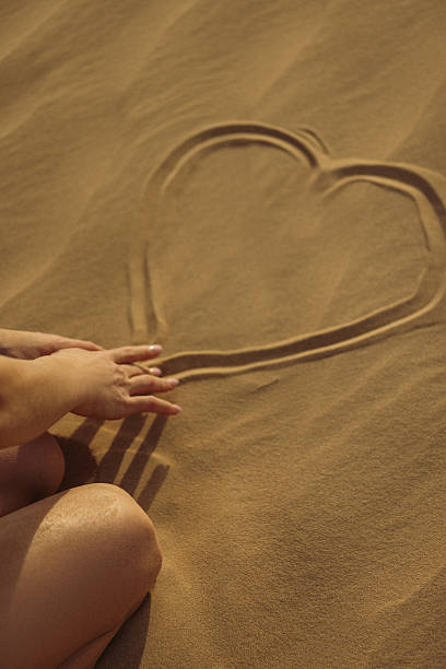 Woman Drawing Heart on Sand at Beach