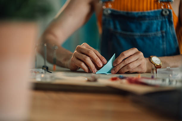 Close-up view of an artist skillfully folding light blue origami paper, crafting a unique art piece in a cozy home workshop setting