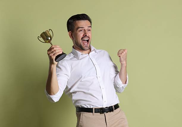 istock Happy winner with golden trophy cup on pale olive background 2219433050