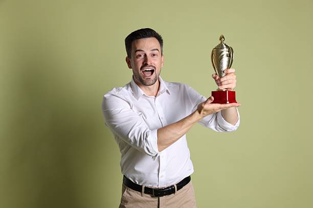 istock Happy winner with golden trophy cup on pale olive background 2219433051