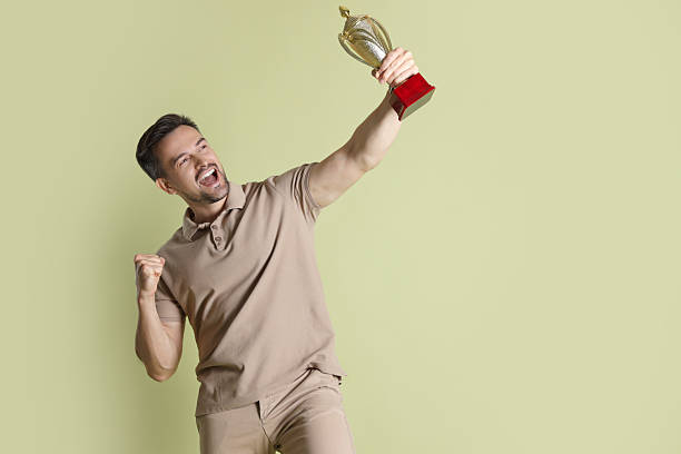 istock Happy winner with golden trophy cup on pale olive background, space for text 2219433130