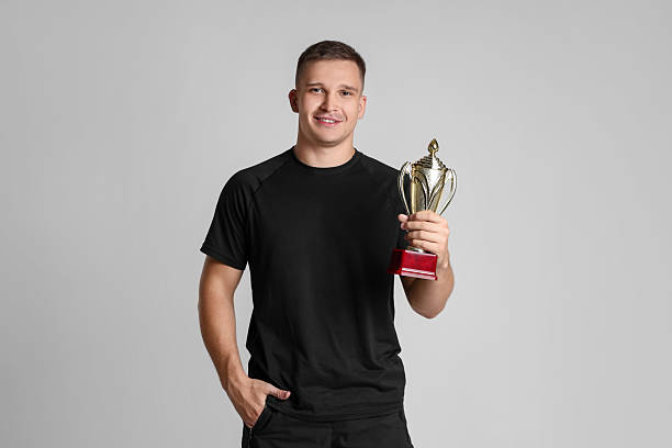 Happy winner with golden trophy cup on light grey background