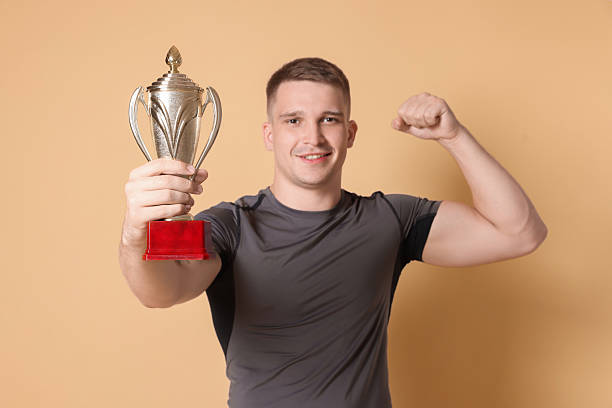 istock Happy winner with golden trophy cup on beige background 2219433174