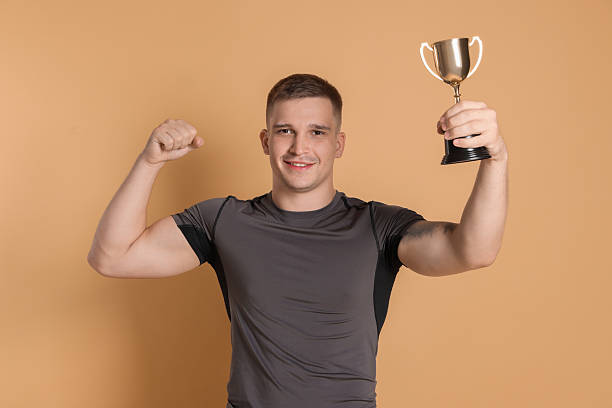 istock Happy winner with golden trophy cup on beige background 2219433231