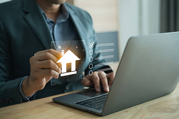 istock Businessman Using Laptop to Access Real Estate Information with House Icon and Data Elements in Modern Office Environment 2219433993