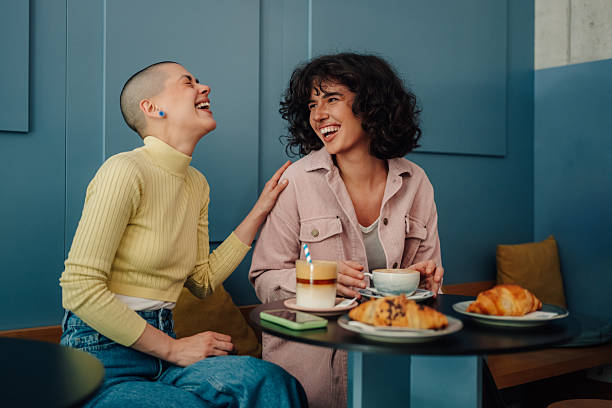 Two young women laughing together at a cafe