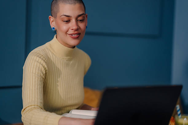 istock Young woman working remotely from home using laptop and textbook 2219435621