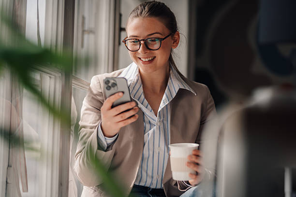 istock Businesswoman using smartphone and drinking coffee during break in office 2219440935