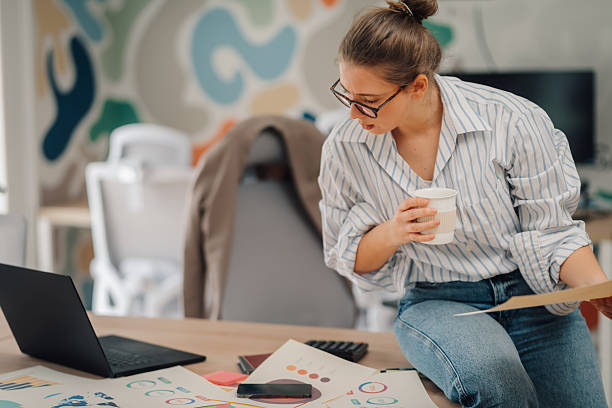 istock Businesswoman analyzing charts and drinking coffee in modern office 2219441080