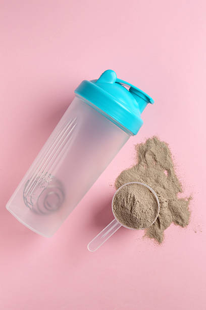 istock Protein powder, scoop and shaker on pink background, flat lay 2219444091