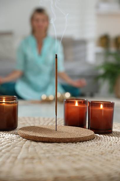 istock Incense stick smoldering in holder and burning candles on wicker mat indoors, selective focus 2219445601