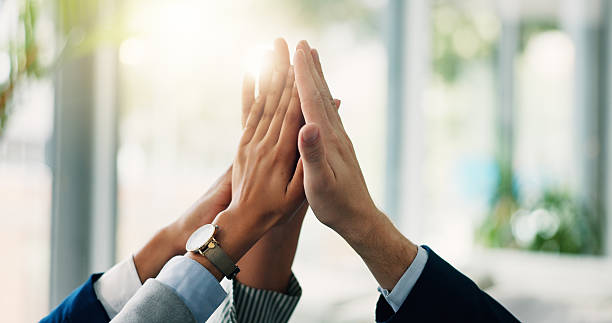 geschäftsleute, hände und teamwork mit high five für meeting, zusammenarbeit oder einheit im büro. nahaufnahme, gruppe oder berührung mit synergie oder lens flare für unternehmenswachstum, -entwicklung oder -verbindung - high five stock-fotos und bilder