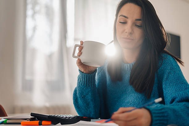 Focused woman drinking coffee while studying at home