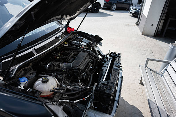 istock Open car hood revealing engine parts with workshop background in sunlight 2219451590