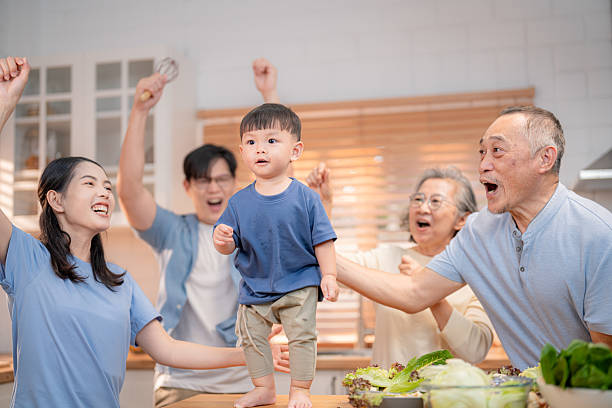 istock Family celebration with a child standing on a table surrounded by joyful relatives in a cozy kitchen 2219451635