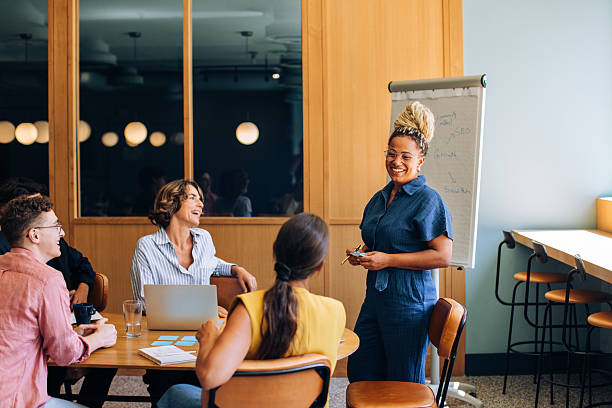 A group of diverse professionals engages in a collaborative meeting, discussing ideas and strategies, in a contemporary office environment featuring a whiteboard and warm, natural lighting.