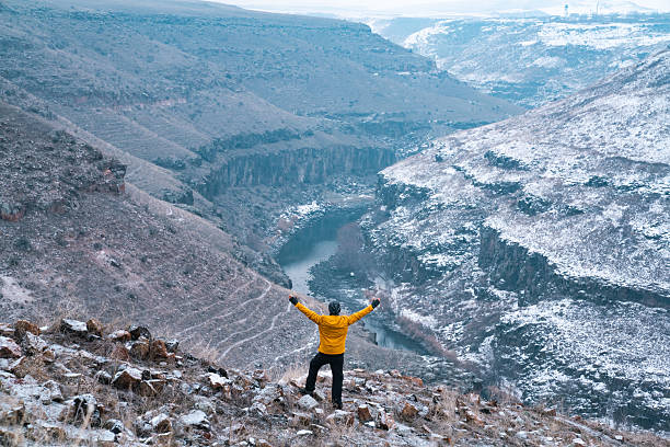 istock A man stands in a snowy canyon with his arms raised 2219457244