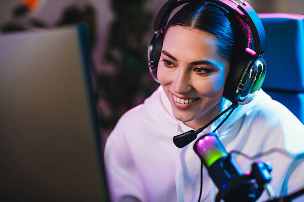istock Positive woman gaming online with headset, illuminated by neon lights, streaming engaging content in a virtual environment 2219457921