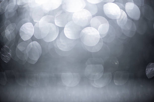 This elegantly abstract, softly defocused and soft focus image displays glowing circles enhanced with subtle shiny glitter textures. With refined silver colored and neutral gray color tones, it evokes an atmosphere of graceful luxury and classic elegance, providing ample copy space as a versatile design element. Ideal for weddings, anniversaries, sophisticated party - social events, festive holidays such as Christmas, New Year's Eve, and romantic celebrations like Valentine's Day - Holiday, it is also perfect for digital web banner, decorative wallpaper - decor, elegant slide show, and creative design uses.