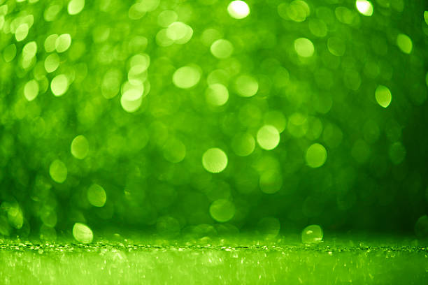 In this green color abstract bokeh backgrounds, finely glittering dust and softly defocused, blurred, glowing circle lights hover over a seamless color gradient, enhancing the rich texture. The wide copy space and focus on foreground transform it into a ready-made template for web banner, header  design element, marketing, sale, business, and event or party  social event use.