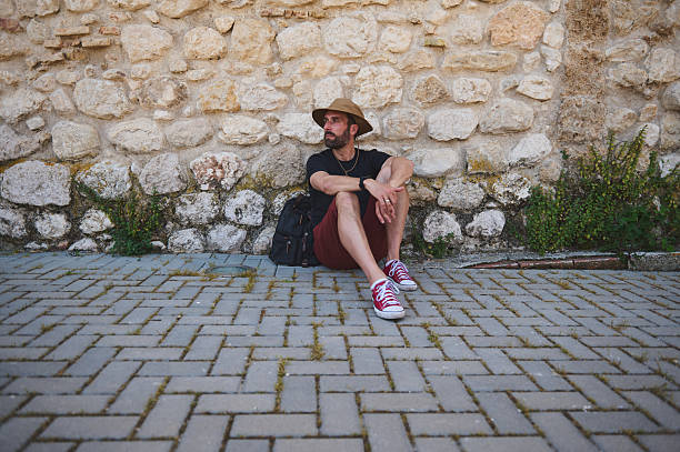 istock Backpack Traveler Sitting Against Brick Wall, Embracing Adventure 2219460559