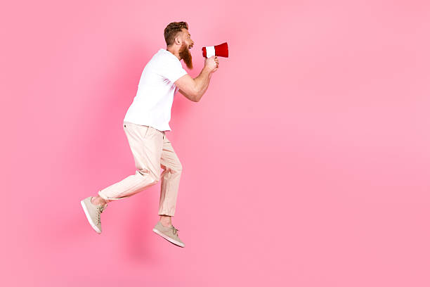 istock Energetic man with a red megaphone making a statement against a vibrant pink backdrop symbolizing communication and promotion 2219460700