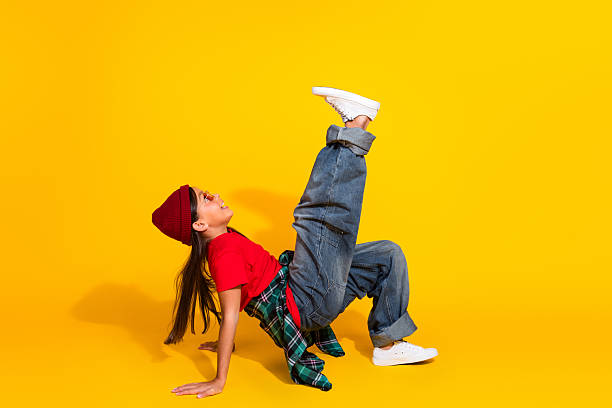 A trendy young girl wearing casual attire posing dynamically against a bright yellow background, expressing fun and a modern lifestyle.