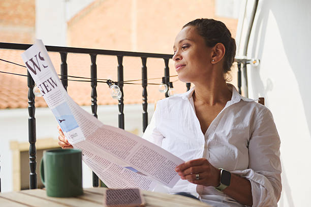 istock Woman Reading Newspaper Outdoors While Relaxing on a Cozy Balcony 2219461341