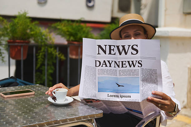 istock Woman Reading a Newspaper Outdoors While Enjoying a Cup of Espresso 2219461371