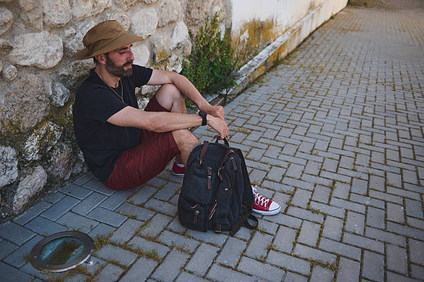 istock Man Resting Against Stone Wall Outdoors With Backpack During an Adventure Journey 2219461403
