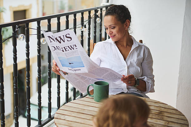 istock Woman Relaxing on Balcony While Reading a Newspaper and Enjoying Coffee 2219461574