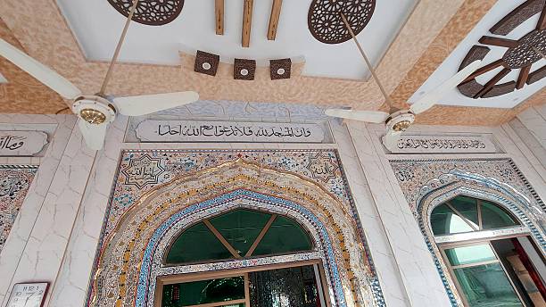 istock A serene and ornate masjid interior features predominantly glasswork walls with intricate patterns and Arabic calligraphy, complemented by a beautifully designed ceiling and fans hanging from the roof 2219463648
