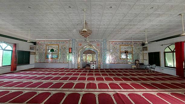 istock A serene and ornate masjid interior features predominantly glasswork walls adorned with intricate patterns and Arabic calligraphy, while the floor is neatly lined with red prayer mats, enhancing the spiritual ambiance 2219463663