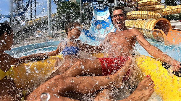 A close-up shot of a group of people splashing in a water slide at an aqua park, capturing the excitement and fun of summer.