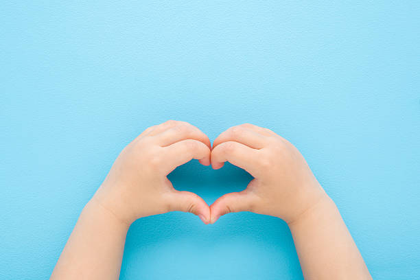 istock Heart shape created from baby boy hands on light blue table background. Pastel color. Love, health and hope concept. Closeup. Point of view shot. Top down view. 2219466447