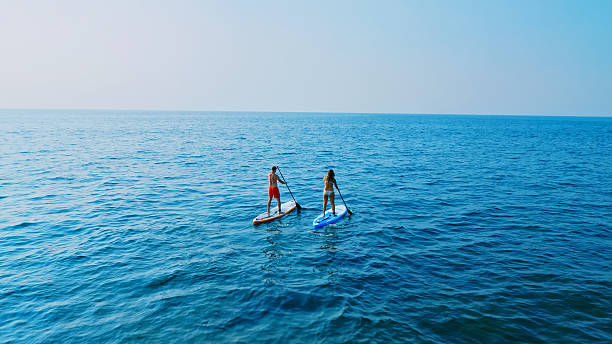 istock Two people paddleboarding on calm ocean waters 2219467632