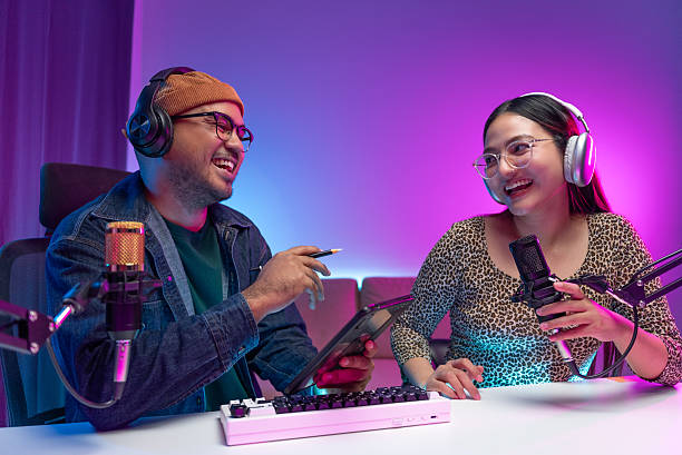 istock Two young asian streamer host making live podcast with condenser microphone and tablet at broadcast home studio. Content creator and social media influencer creating digital content. 2219468211