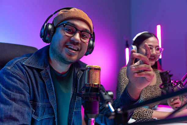 istock Two young asian streamer host making live podcast with condenser microphone and tablet at broadcast home studio. Content creator and social media influencer creating digital content. 2219468222
