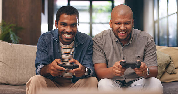 istock Home, friends and gaming with controller on sofa for multiplayer, competition and entertainment. Happy, people and men with smile in living room for esports challenge, streaming and playful contest 2219469698