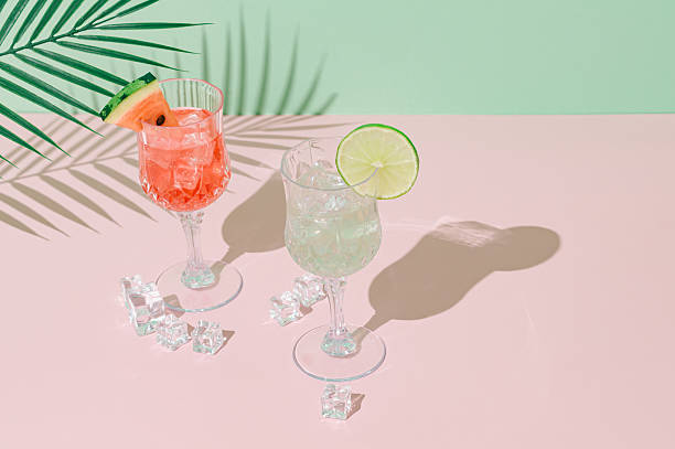 istock Summer scene with refreshing watermelon and lime drinks and palm leaves shadow on pink and green background. Sun and shadows. Minimal cocktail concept. Trendy summertime party idea. Summer aesthetic. 2219470548