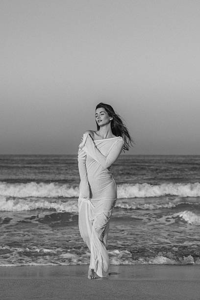 istock Woman in white dress on beach with serene and reflective expression 2219474556